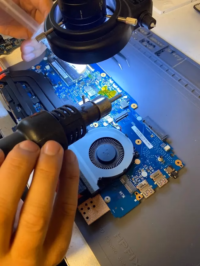 Technician using hot-air equipment for laptop motherboard repair at Indy Laptops in Indianapolis